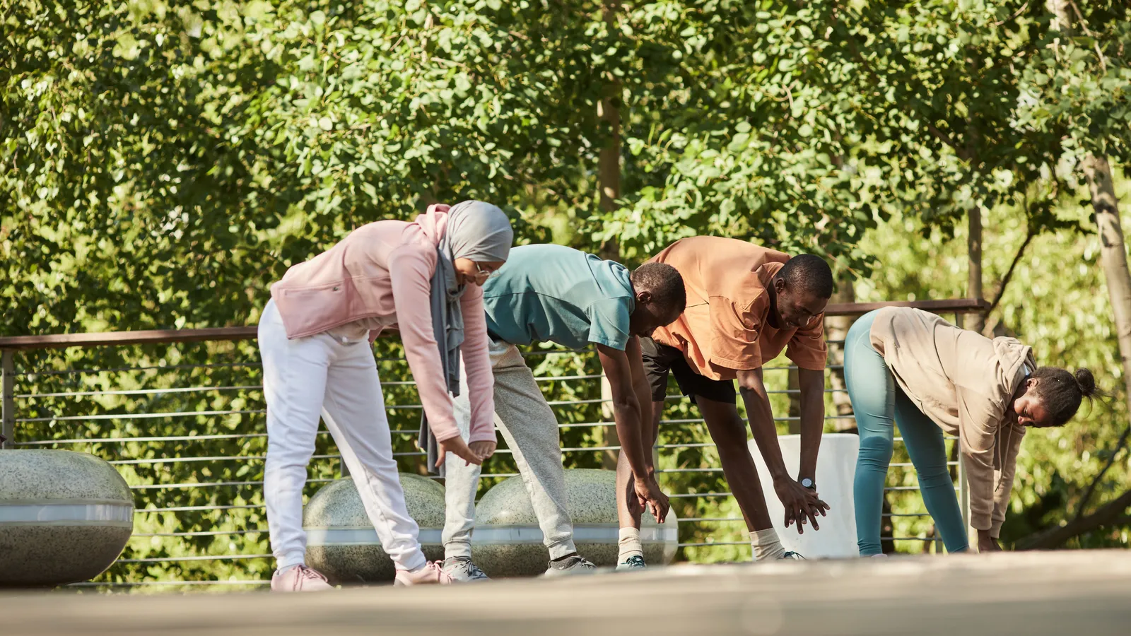 A diverse group of adults stretches together outdoors.